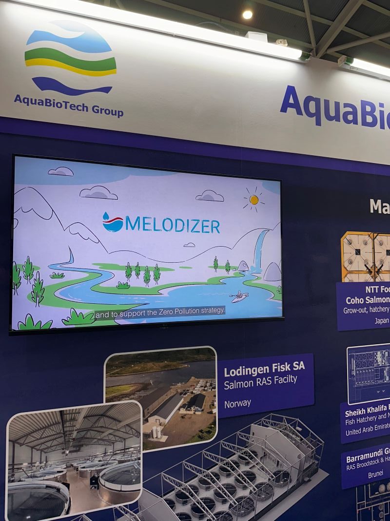 melodizer-aquabiotech-world-aquaculture-2026 AquaBioTech representative at the MEloDIZER booth during World Aquaculture 2026 in Singapore, with project brochures and dissemination materials on display.
