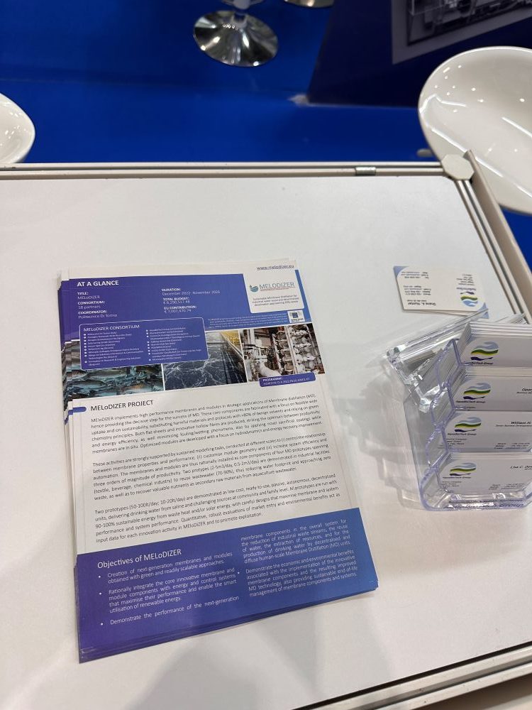melodizer-aquabiotech-world-aquaculture-2026 AquaBioTech representative at the MEloDIZER booth during World Aquaculture 2026 in Singapore, with project brochures and dissemination materials on display.